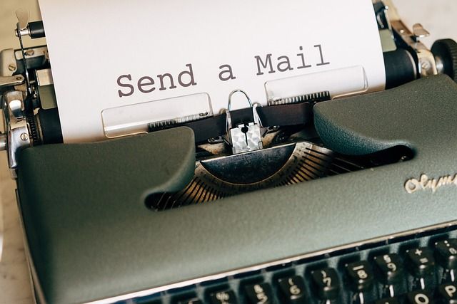 Mechanische Schreibmaschine mit einem weißen Blatt Papier. Auf dem Papier steht Send a Mail geschrieben