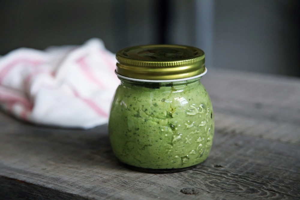 Pestoglas mit Radieschengrün-Pesto neben Geschirrtuch